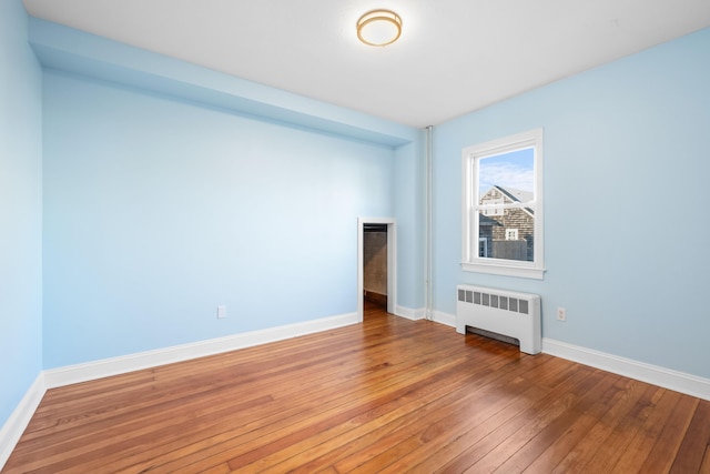 empty room featuring wood-type flooring and radiator heating unit