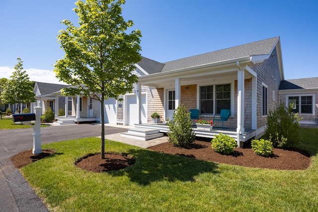 view of front of home featuring a garage, covered porch, and a front lawn