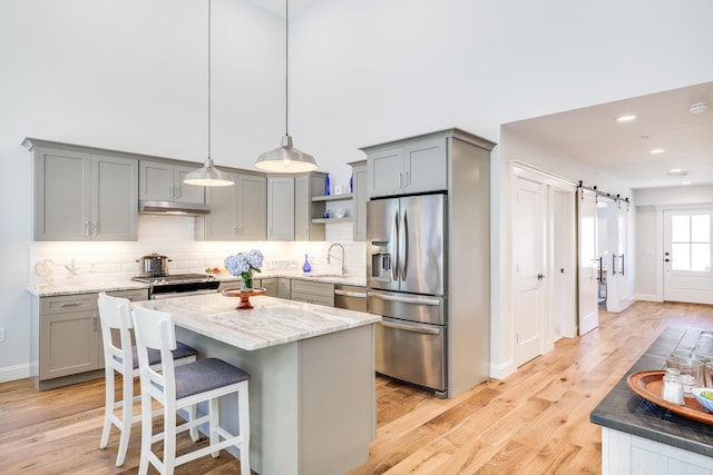 kitchen featuring sink, decorative light fixtures, a barn door, a kitchen island, and stainless steel appliances