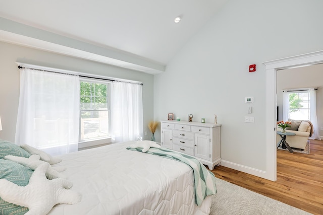 bedroom with high vaulted ceiling, light hardwood / wood-style flooring, and multiple windows