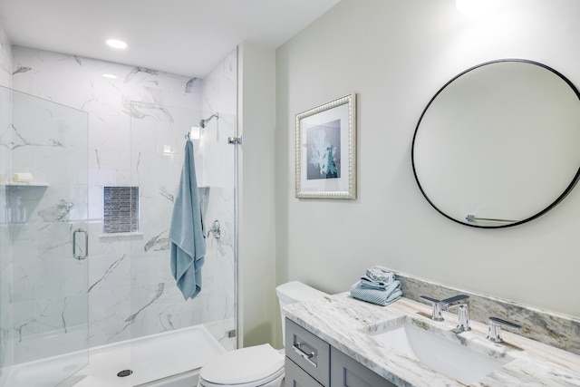 bathroom featuring a shower with door, toilet, and vanity