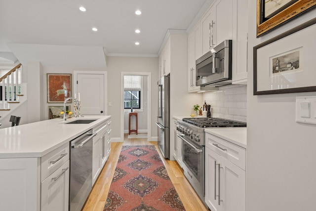 350 Bradford St Unit U7, Provincetown, MA 02657 - kitchen featuring high quality appliances, a sink, ornamental molding, white cabinetry, and light wood-style floors