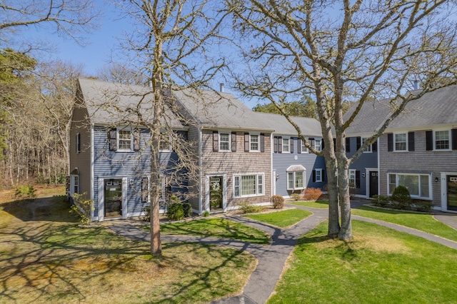 view of front of house with a front yard and a shingled roof