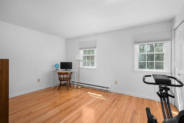 office space with a wealth of natural light, baseboards, baseboard heating, and wood-type flooring