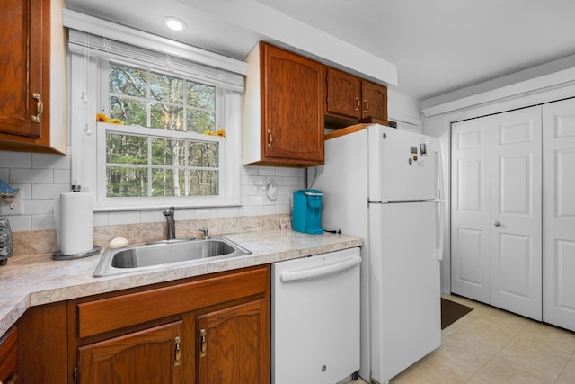 kitchen with light tile patterned floors, white appliances, light countertops, and a sink