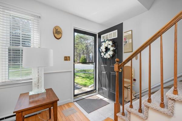 entryway featuring stairs, baseboard heating, and wood finished floors