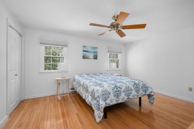 bedroom with baseboards, light wood-style floors, multiple windows, and a closet