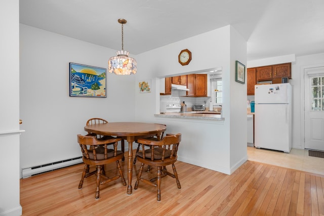 dining space with baseboard heating and light wood-style flooring