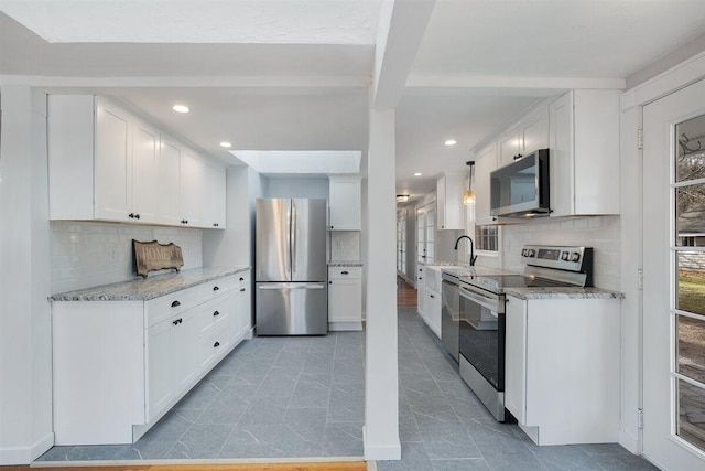 kitchen with sink, white cabinetry, decorative backsplash, and stainless steel appliances