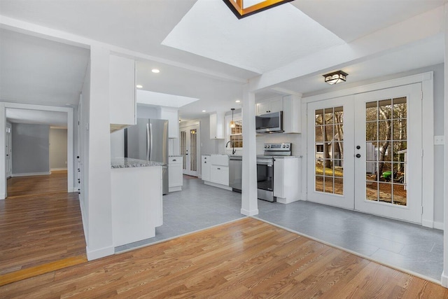 kitchen with white cabinets, light hardwood / wood-style floors, and appliances with stainless steel finishes