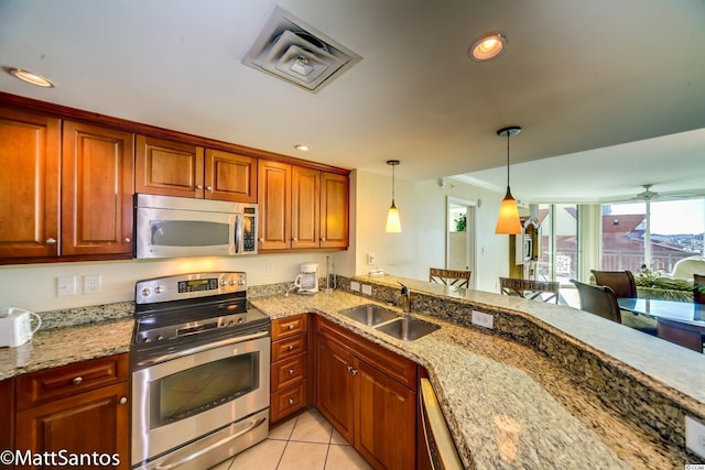 kitchen featuring light tile patterned flooring, stainless steel appliances, light stone countertops, pendant lighting, and sink