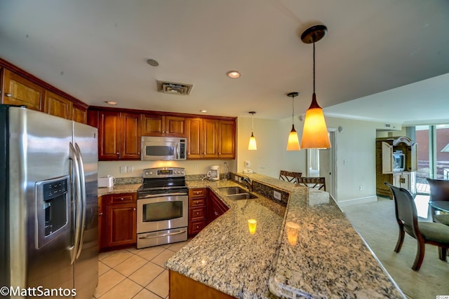 kitchen featuring stainless steel appliances, sink, kitchen peninsula, light stone countertops, and hanging light fixtures