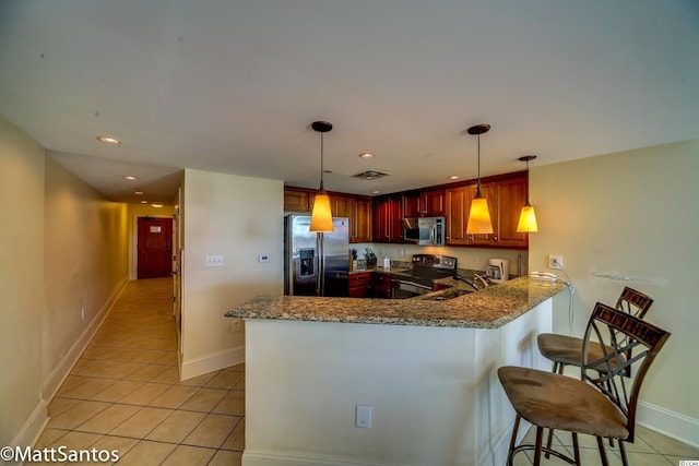 kitchen with kitchen peninsula, hanging light fixtures, a breakfast bar, appliances with stainless steel finishes, and dark stone countertops