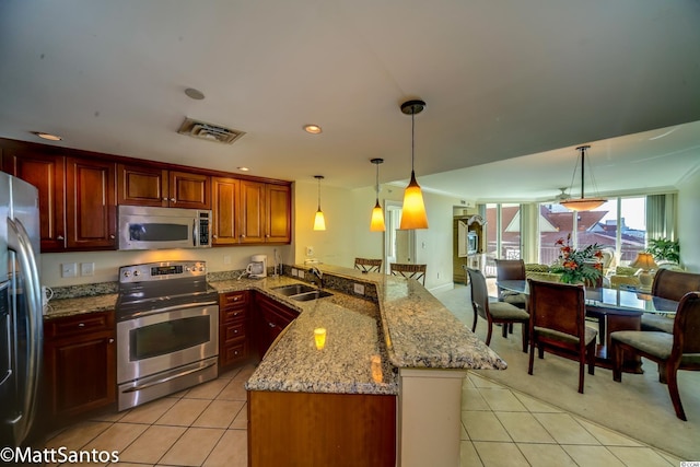 kitchen with sink, kitchen peninsula, appliances with stainless steel finishes, hanging light fixtures, and light colored carpet