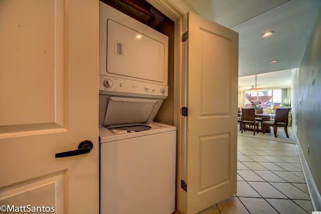 clothes washing area featuring stacked washing maching and dryer and light tile patterned floors