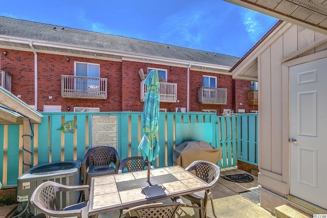 view of patio with a balcony and central air condition unit