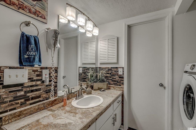 bathroom with tasteful backsplash, washer / clothes dryer, a textured ceiling, and vanity