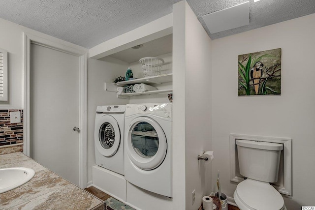 laundry room with independent washer and dryer, sink, and a textured ceiling