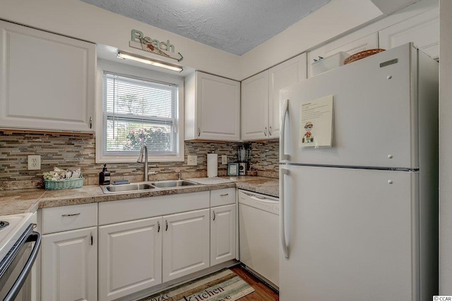 kitchen with white appliances, white cabinetry, and sink