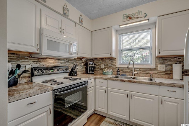 kitchen with white cabinets, backsplash, white appliances, and sink