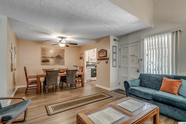 living room featuring ceiling fan, a textured ceiling, and light hardwood / wood-style floors