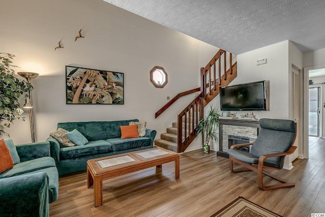 living room with a fireplace, a textured ceiling, and light wood-type flooring