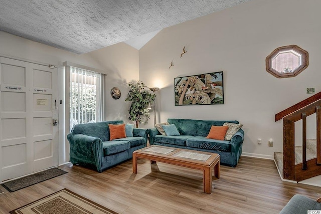 living room with lofted ceiling, a textured ceiling, and light wood-type flooring