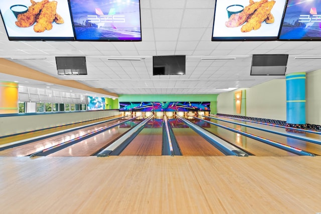 rec room with a paneled ceiling, a bowling alley, and wood-type flooring