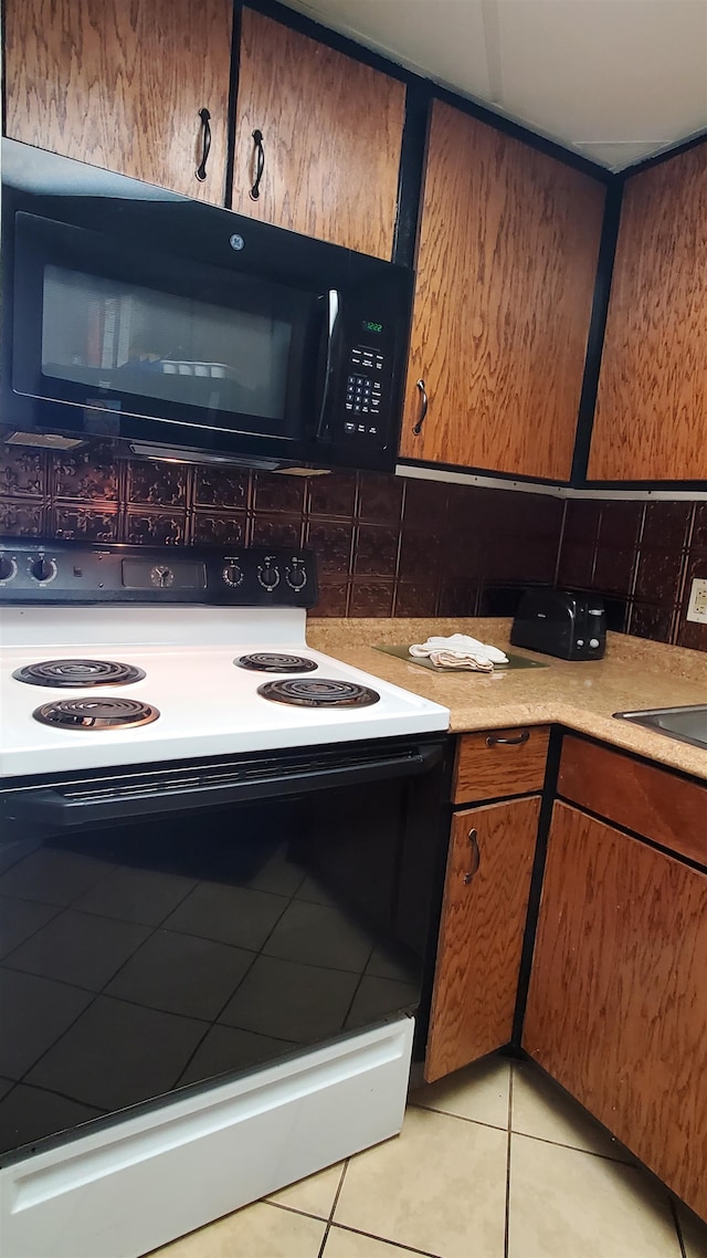 kitchen featuring white electric stove, backsplash, and light tile floors