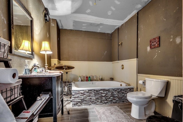 bathroom featuring lofted ceiling, toilet, vanity, and a relaxing tiled bath