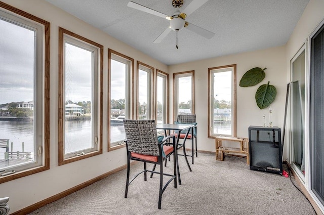 sunroom / solarium featuring ceiling fan, a water view, and a healthy amount of sunlight