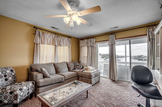 carpeted living room featuring a textured ceiling, ceiling fan, and a water view