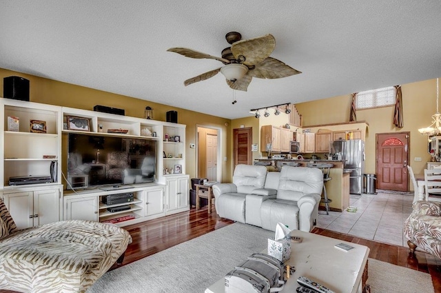 living room featuring light tile flooring, a textured ceiling, and ceiling fan with notable chandelier