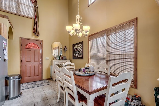 tiled dining area with a chandelier and a high ceiling