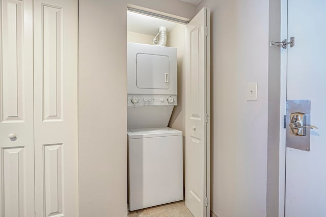 laundry room featuring stacked washer / drying machine and light tile floors