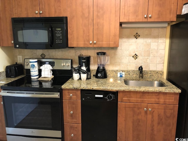 kitchen featuring light stone countertops, tasteful backsplash, black appliances, and sink