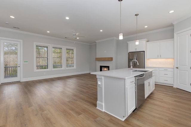 kitchen featuring a large fireplace, an island with sink, appliances with stainless steel finishes, and white cabinets