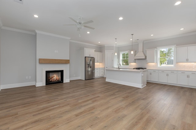 kitchen with custom exhaust hood, a kitchen island with sink, stainless steel fridge with ice dispenser, white cabinets, and decorative light fixtures