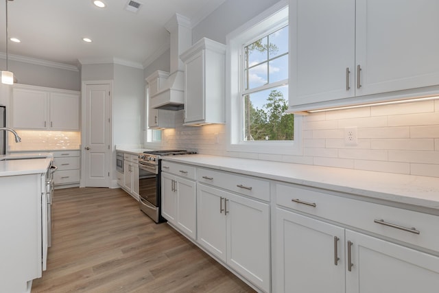 kitchen with sink, white cabinets, light stone counters, stainless steel gas range oven, and hanging light fixtures