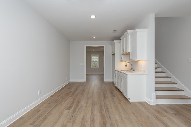 kitchen featuring sink, white cabinetry, and light wood-type flooring