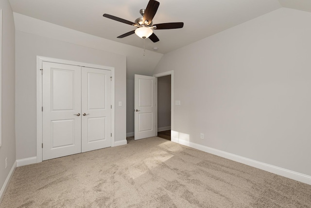 unfurnished bedroom featuring ceiling fan, a closet, light carpet, and vaulted ceiling