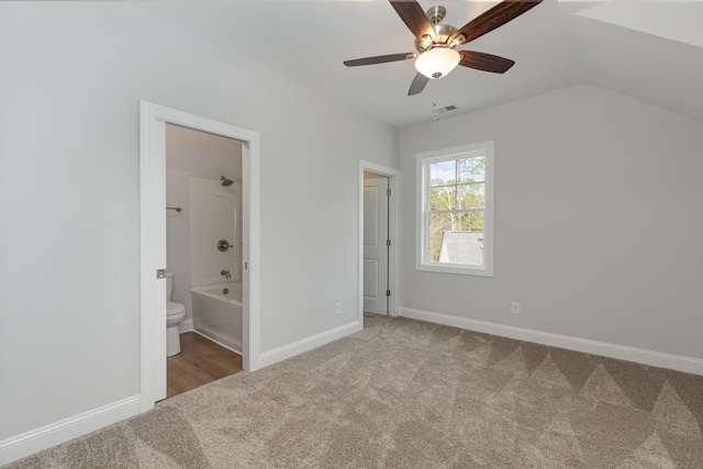 unfurnished bedroom with vaulted ceiling, carpet floors, ceiling fan, and connected bathroom