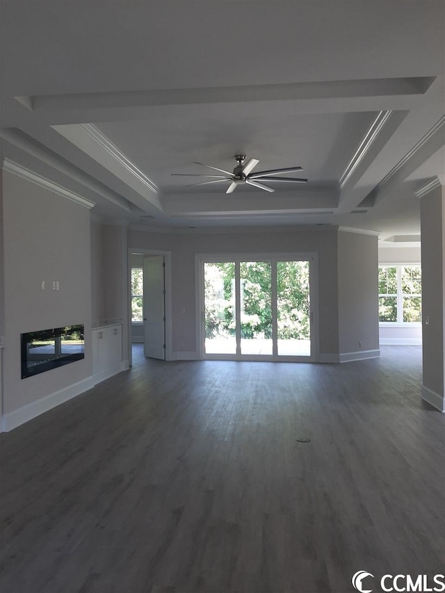 unfurnished living room with dark hardwood / wood-style flooring, ceiling fan, crown molding, and a tray ceiling