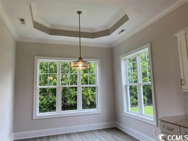 unfurnished room with crown molding, light wood-type flooring, and a tray ceiling