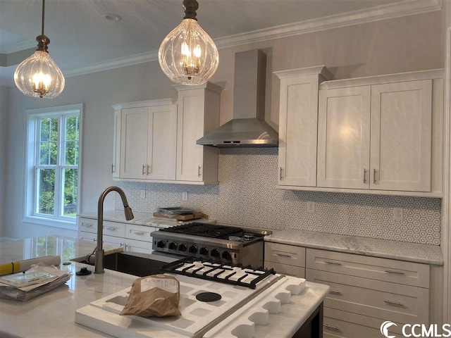 kitchen with wall chimney range hood, backsplash, decorative light fixtures, white cabinetry, and crown molding