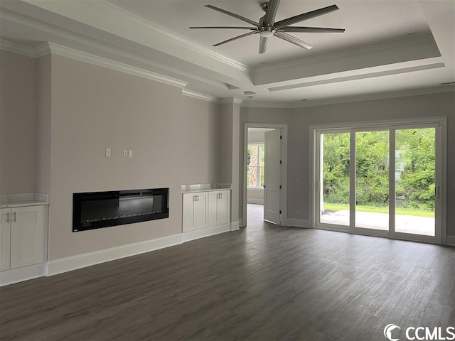 unfurnished living room with dark hardwood / wood-style flooring, ceiling fan, ornamental molding, and a tray ceiling