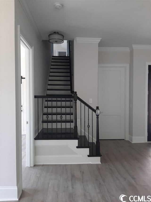 stairway with ornamental molding and light hardwood / wood-style flooring