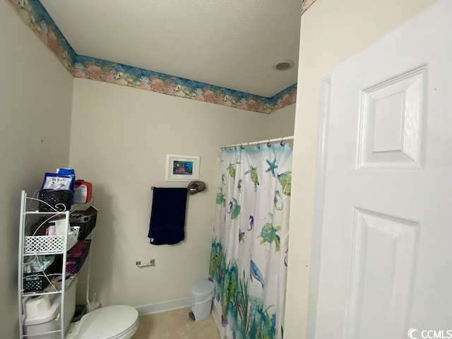 bathroom featuring a textured ceiling, tile flooring, and toilet