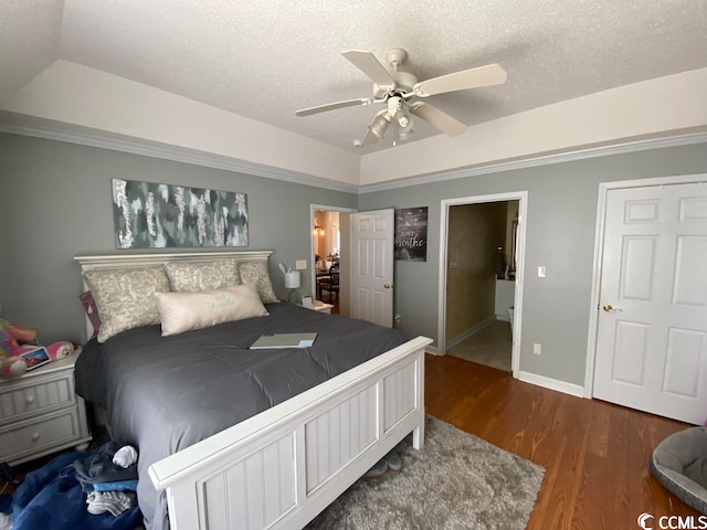 bedroom with ceiling fan, a textured ceiling, dark wood-type flooring, and a tray ceiling