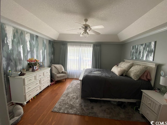 bedroom with ceiling fan, a textured ceiling, a tray ceiling, and wood-type flooring